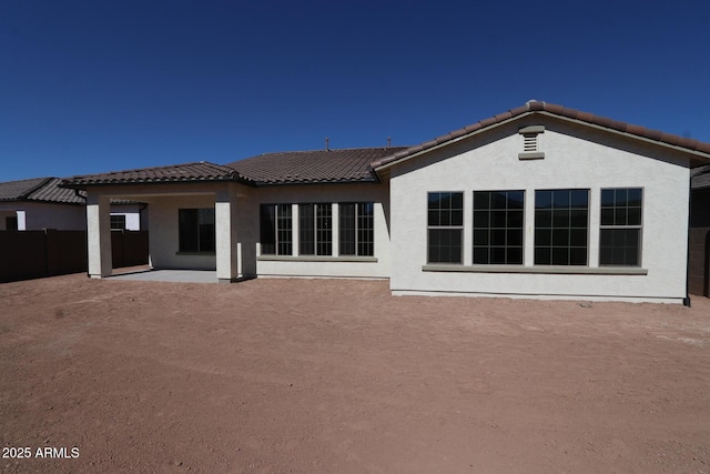 back of property with fence, stucco siding, a tiled roof, and a patio