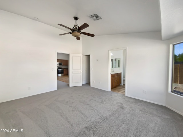 unfurnished bedroom with light carpet, connected bathroom, vaulted ceiling, and ceiling fan