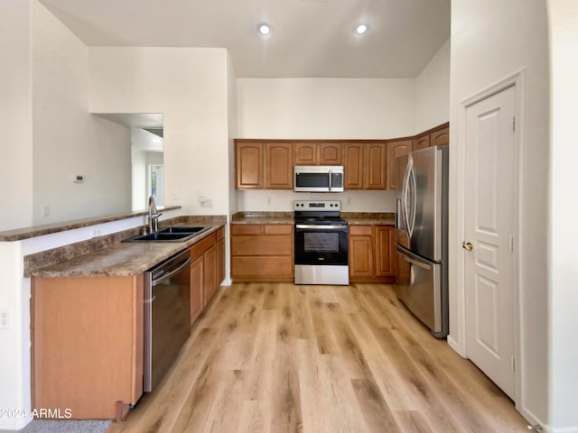 kitchen with light hardwood / wood-style floors, sink, kitchen peninsula, and stainless steel appliances