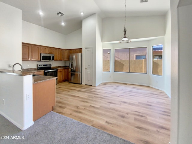 kitchen featuring high vaulted ceiling, light hardwood / wood-style floors, stainless steel appliances, and hanging light fixtures