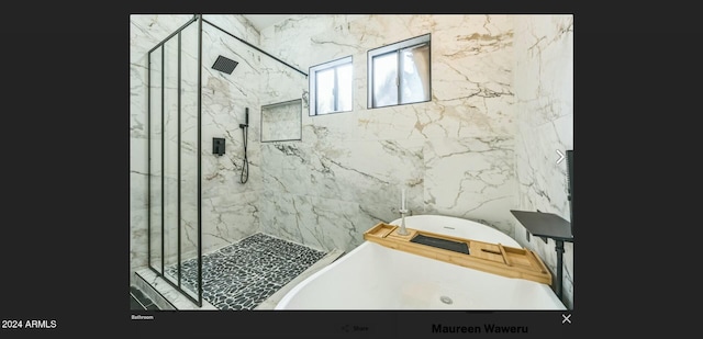 bathroom featuring plus walk in shower and tile walls