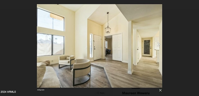 living room with hardwood / wood-style floors, high vaulted ceiling, and a notable chandelier