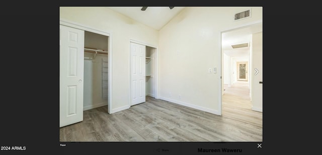 unfurnished bedroom featuring ceiling fan, light hardwood / wood-style floors, and vaulted ceiling