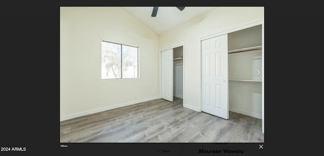 unfurnished bedroom with multiple closets, ceiling fan, light hardwood / wood-style floors, and vaulted ceiling