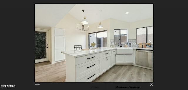 kitchen with white cabinetry, sink, hanging light fixtures, light hardwood / wood-style flooring, and stainless steel dishwasher