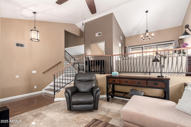 living room with ceiling fan with notable chandelier and high vaulted ceiling