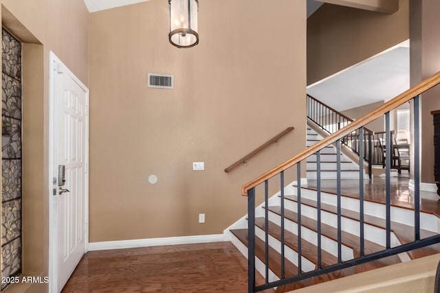 staircase with a high ceiling and hardwood / wood-style flooring