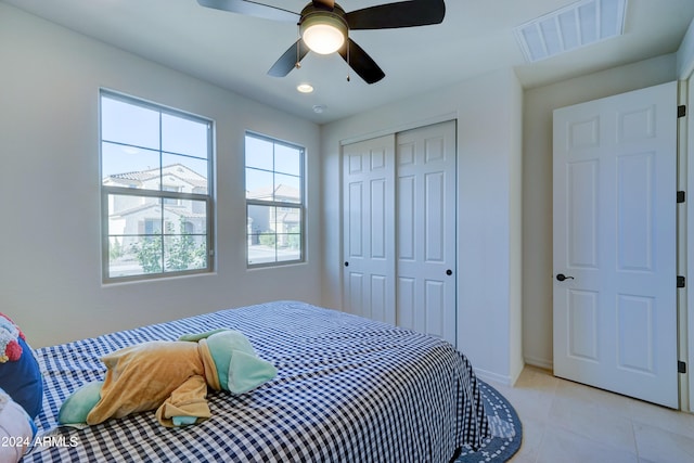 tiled bedroom with ceiling fan and a closet