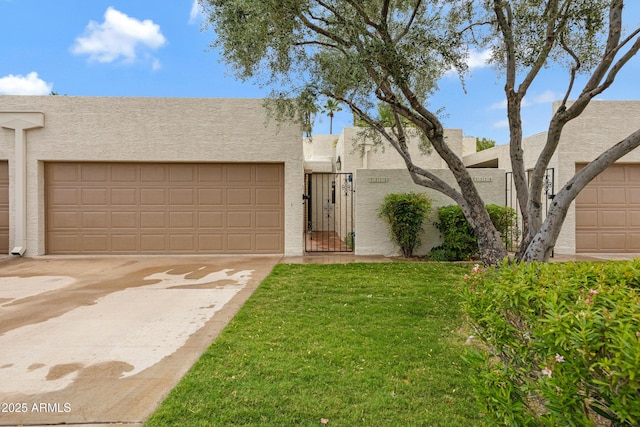 adobe home with stucco siding, driveway, a gate, and a front yard