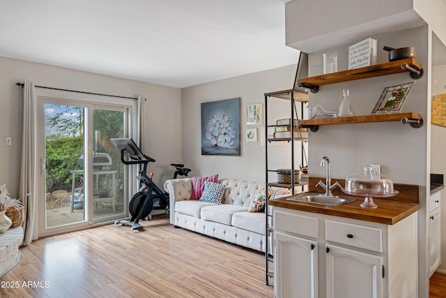 exercise room featuring light wood finished floors and wet bar
