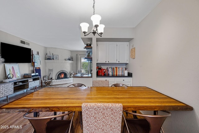 dining space featuring a chandelier, a brick fireplace, and wood finished floors