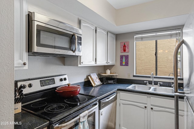 kitchen with stainless steel appliances, a sink, white cabinets, and dark countertops