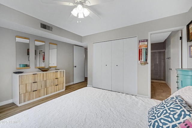 bedroom with wood finished floors, baseboards, a closet, and connected bathroom