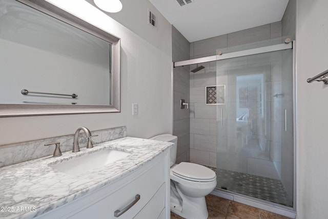 bathroom featuring a shower stall, toilet, vanity, and tile patterned floors