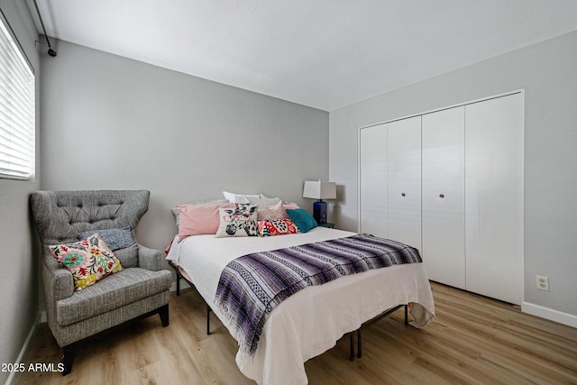bedroom with light wood-type flooring, baseboards, and a closet