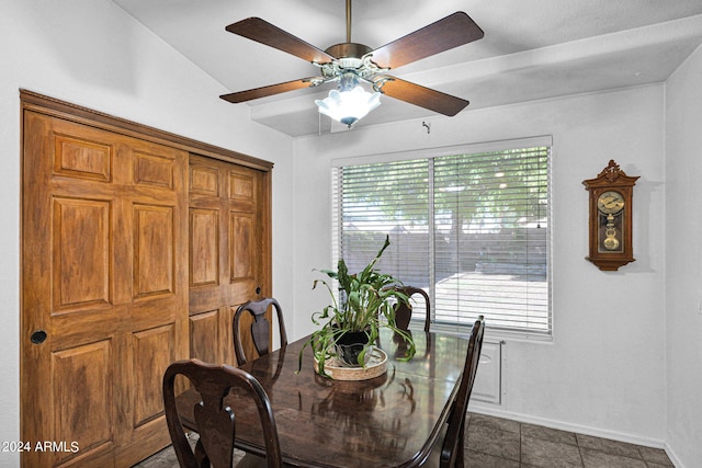 dining room with vaulted ceiling, dark tile patterned flooring, and ceiling fan