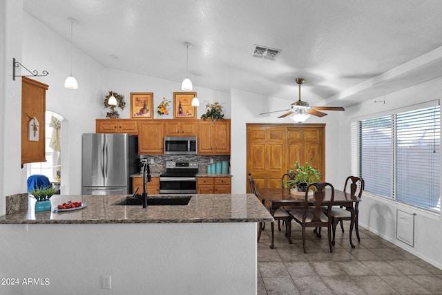 kitchen featuring appliances with stainless steel finishes, hanging light fixtures, lofted ceiling, and sink