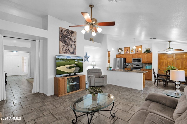 living room featuring ceiling fan, high vaulted ceiling, and a textured ceiling