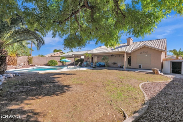 back of property with a patio, a fenced in pool, and ceiling fan