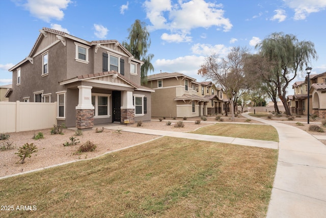 view of front facade featuring fence, stone siding, a residential view, stucco siding, and a front lawn