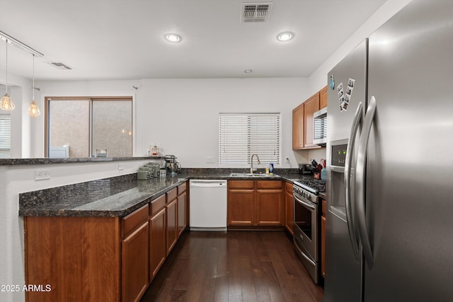 kitchen with stainless steel appliances, dark wood-type flooring, a peninsula, a sink, and visible vents