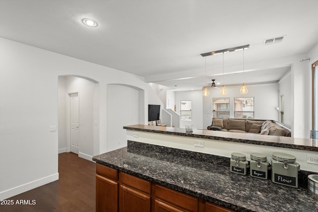 kitchen with visible vents, open floor plan, dark stone counters, dark wood finished floors, and pendant lighting