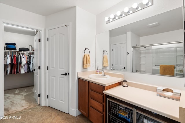 bathroom featuring an enclosed shower, a walk in closet, and vanity