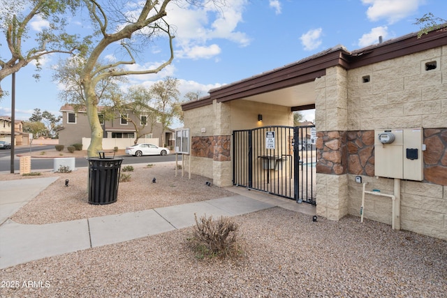 exterior space with stone siding and a gate