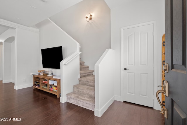 foyer entrance featuring baseboards, stairway, arched walkways, and wood finished floors