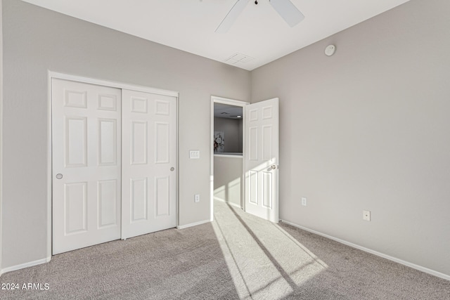 unfurnished bedroom featuring light carpet, a closet, and ceiling fan