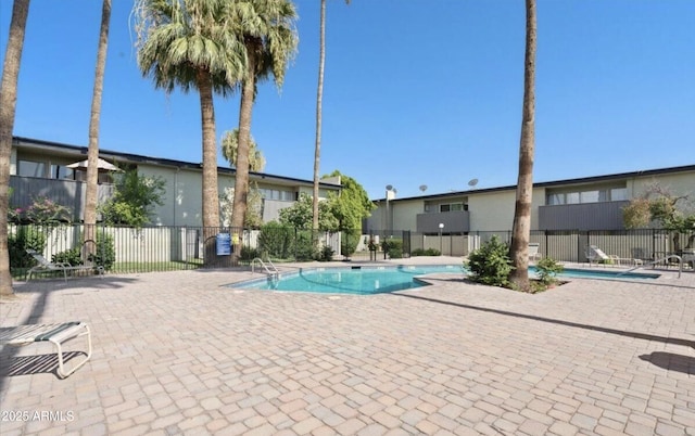 community pool with a patio area and fence