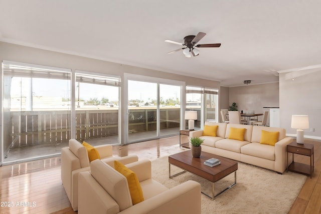 living area with plenty of natural light, wood-type flooring, a ceiling fan, and crown molding