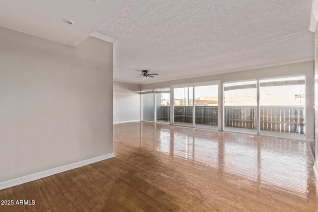 spare room featuring a textured ceiling, hardwood / wood-style floors, a ceiling fan, and baseboards