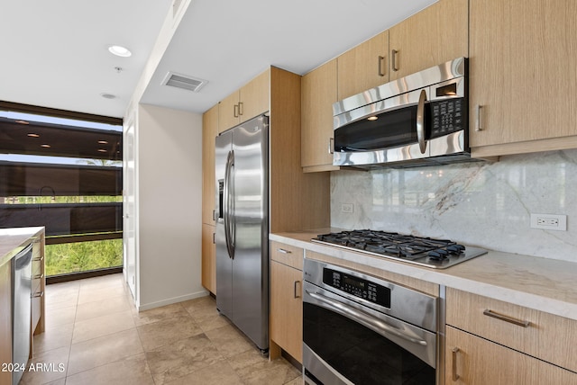 kitchen featuring decorative backsplash, stainless steel appliances, and light brown cabinetry