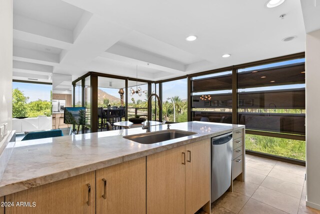 kitchen with light stone countertops, light brown cabinetry, sink, dishwasher, and light tile patterned flooring