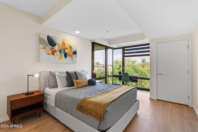 bedroom with light hardwood / wood-style floors and a wall of windows