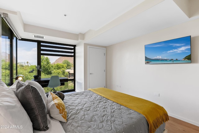 bedroom with hardwood / wood-style floors and multiple windows