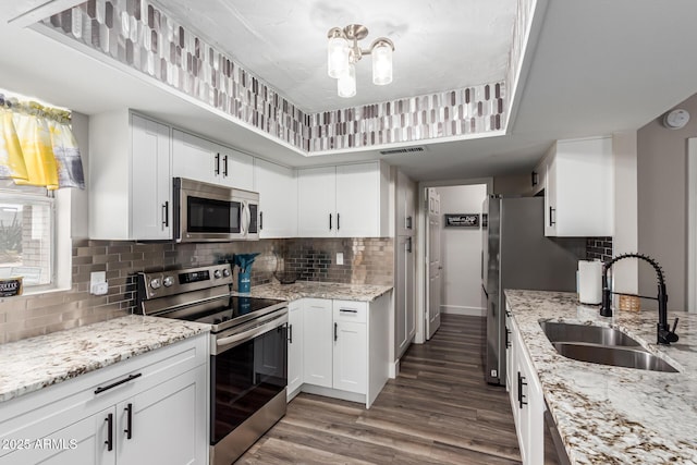 kitchen with a notable chandelier, a sink, stainless steel appliances, decorative backsplash, and wood finished floors