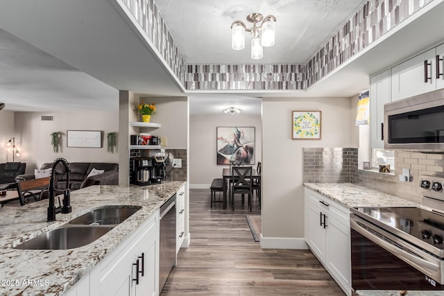 kitchen with wood finished floors, baseboards, tasteful backsplash, a sink, and appliances with stainless steel finishes
