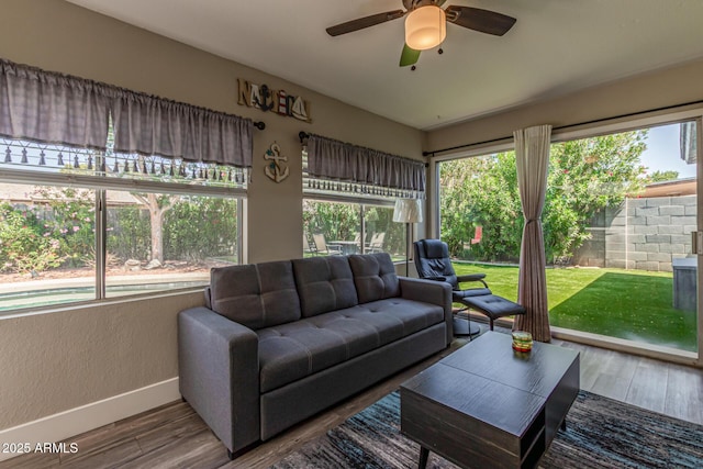 living room with a ceiling fan, baseboards, and wood finished floors