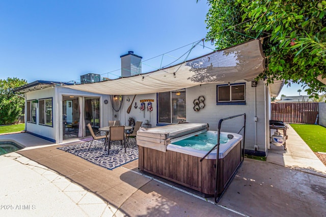 rear view of house featuring fence, a chimney, a hot tub, and a patio area