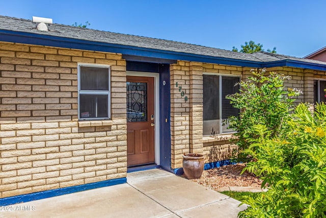 entrance to property with brick siding and roof with shingles