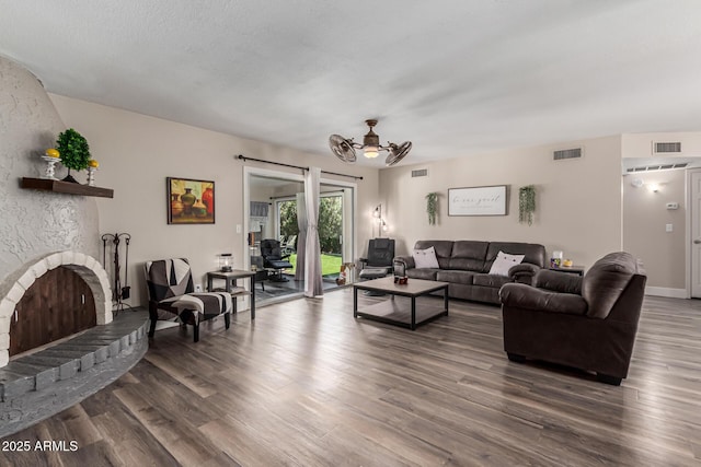 living area featuring dark wood-style flooring, visible vents, and a fireplace with raised hearth