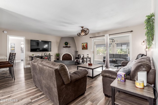 living area featuring baseboards, wood finished floors, and a large fireplace