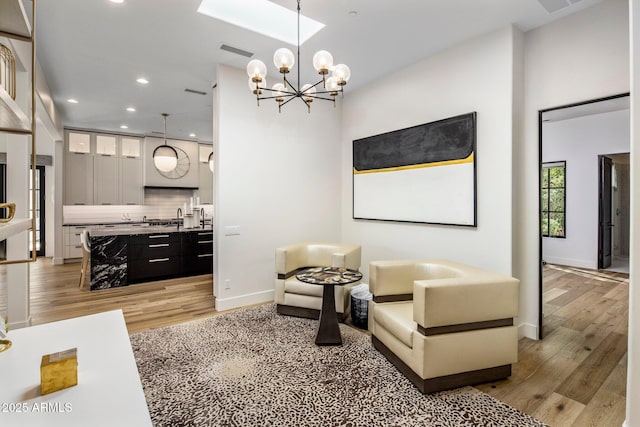 living area with a notable chandelier, light wood finished floors, recessed lighting, visible vents, and baseboards