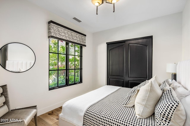 bedroom with visible vents, baseboards, and wood finished floors