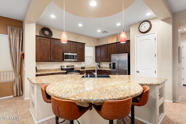 kitchen featuring sink, a center island with sink, decorative light fixtures, and appliances with stainless steel finishes