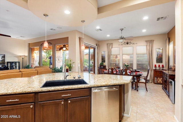 kitchen with decorative light fixtures, ceiling fan, light stone counters, and sink