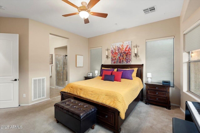 bedroom with ensuite bathroom, light colored carpet, and ceiling fan