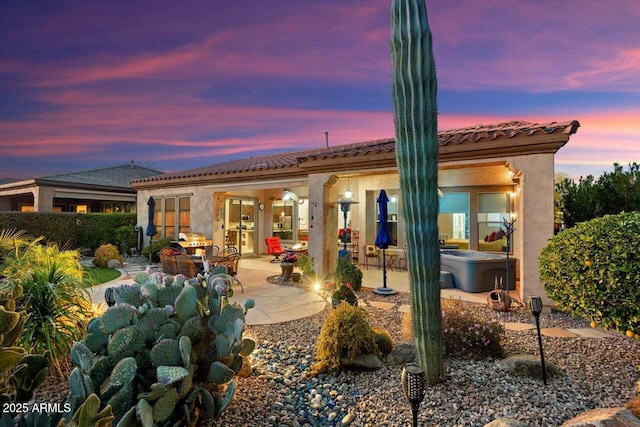 back house at dusk with a patio